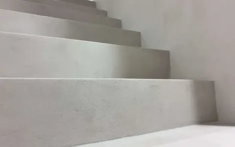 Nowoczesne schody z surowego betonu na klatce schodowej. Minimalistyczny design, jasnoszare stopnie.