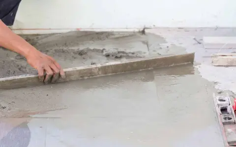 Ręka wyrównuje świeży beton, tworząc tanią podłogę z betonu.