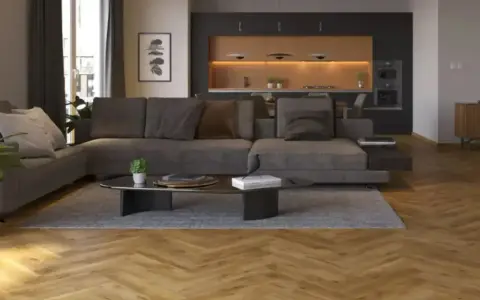 Nowoczesny salon z szarą kanapą i czarną ścianą w tle. Drewniana podłoga w jodełkę dodaje ciepła.