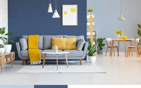 Nowoczesny salon z szarą kanapą, żółtymi poduszkami i kocem. Ściany w odcieniach niebieskiego koloru ścian tworzą przytulną atmosferę.