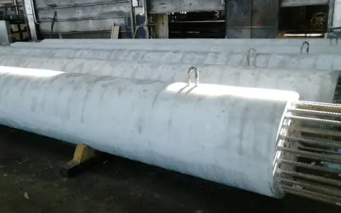 Długie, betonowe rury leżą obok siebie. Widać metalowe uchwyty do transportu. To efekt pracy z szalunkiem papierowym, który nadał im idealny kształt.