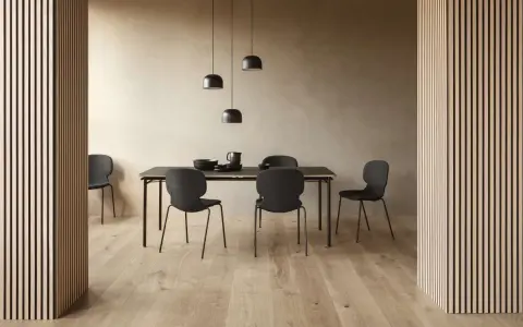 Jadalnia w stylu soft minimalism: czarne krzesła i stół na tle beżowej ściany, oświetlone lampami.