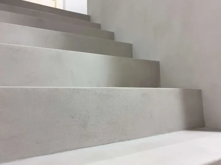 Nowoczesne schody z surowego betonu na klatce schodowej. Minimalistyczny design, jasnoszare stopnie.