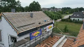 Budowa dachu z blachą i membraną. Pracownik na rusztowaniu montuje pokrycie.