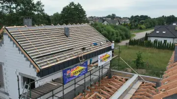 Budowa dachu z blachą i membraną. Pracownik na rusztowaniu montuje pokrycie.
